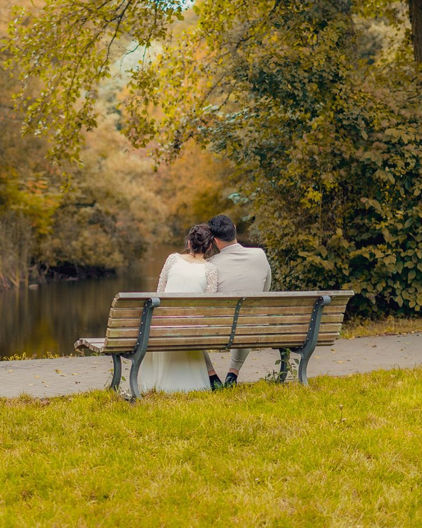 Brautpaar auf einer Bank am See im Herbst