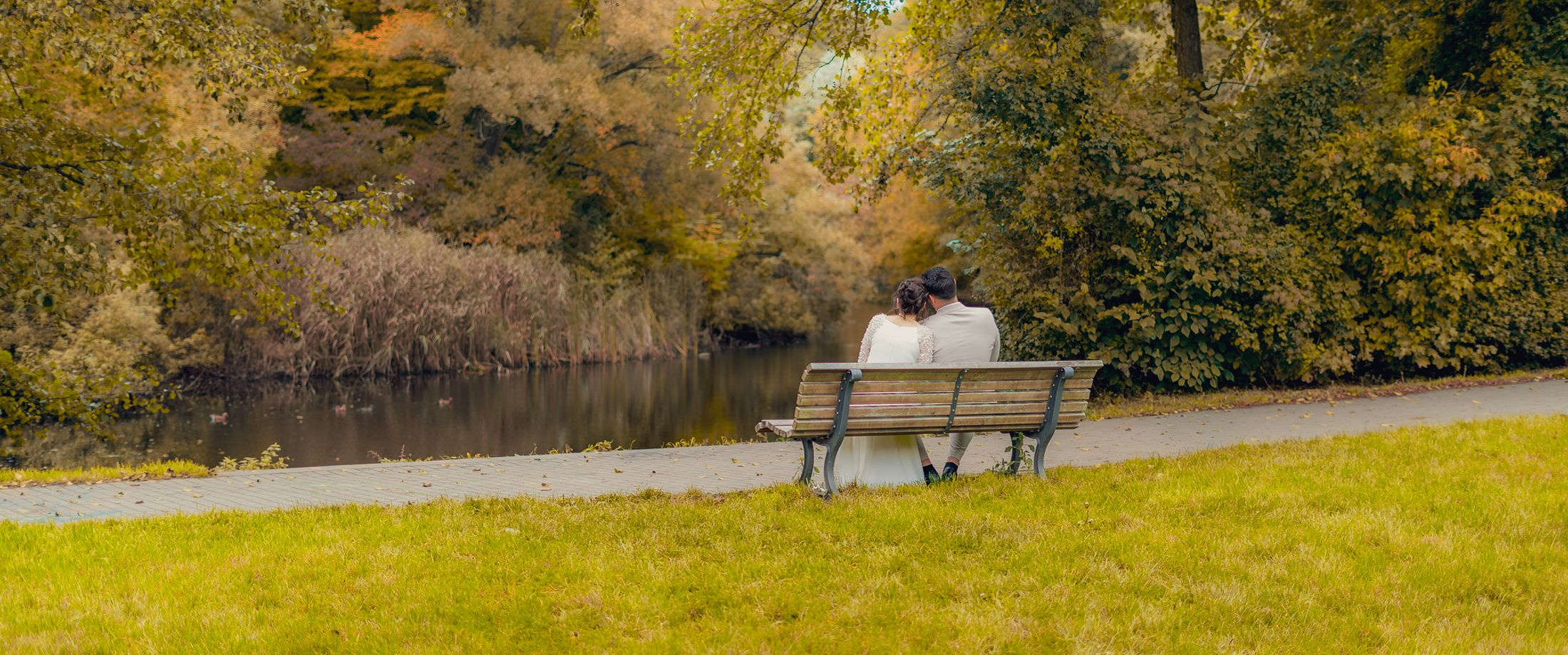 Brautpaar auf einer Bank am See im Herbst, fotografiert von Swordmedia